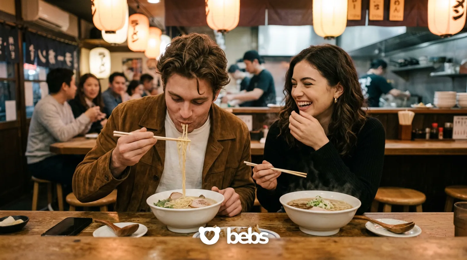 Couple laughing over ramen at a cozy noodle bar on their first date after weeks of texting, moving from texts to a real date